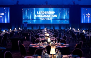 crowded banquet setting with a lit screen that says leadership and recognition awards