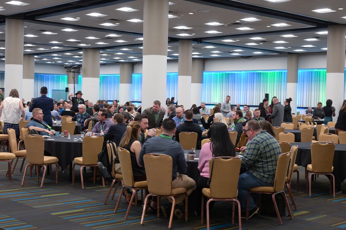 Participants assis à des tables rondes dans une salle de conférence aux fenêtres éclairées en bleu
