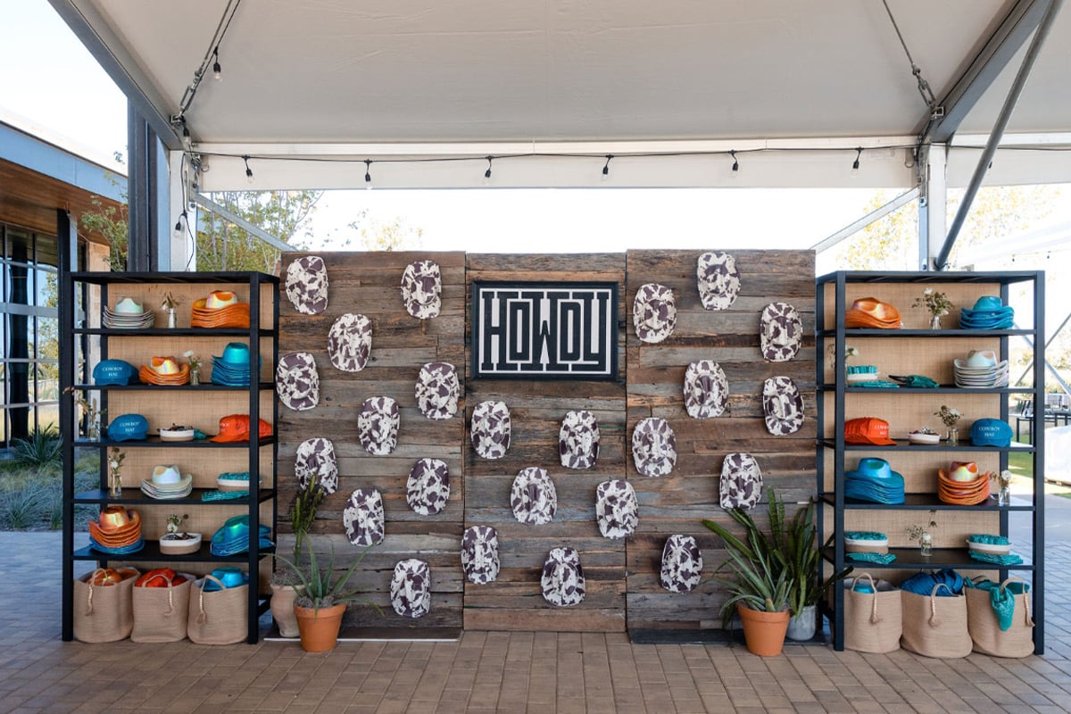 Présentoir mural en bois rustique avec de l'art en peau de vache et des poteries turquoise et orange sur des étagères adjacentes.