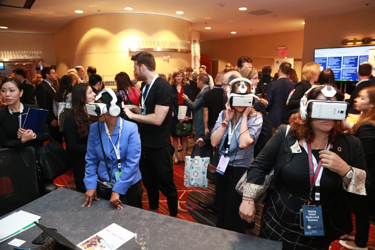 Les participants à la conférence utilisent des casques de réalité virtuelle dans un hall d'exposition bondé où les écrans de présentation sont visibles.