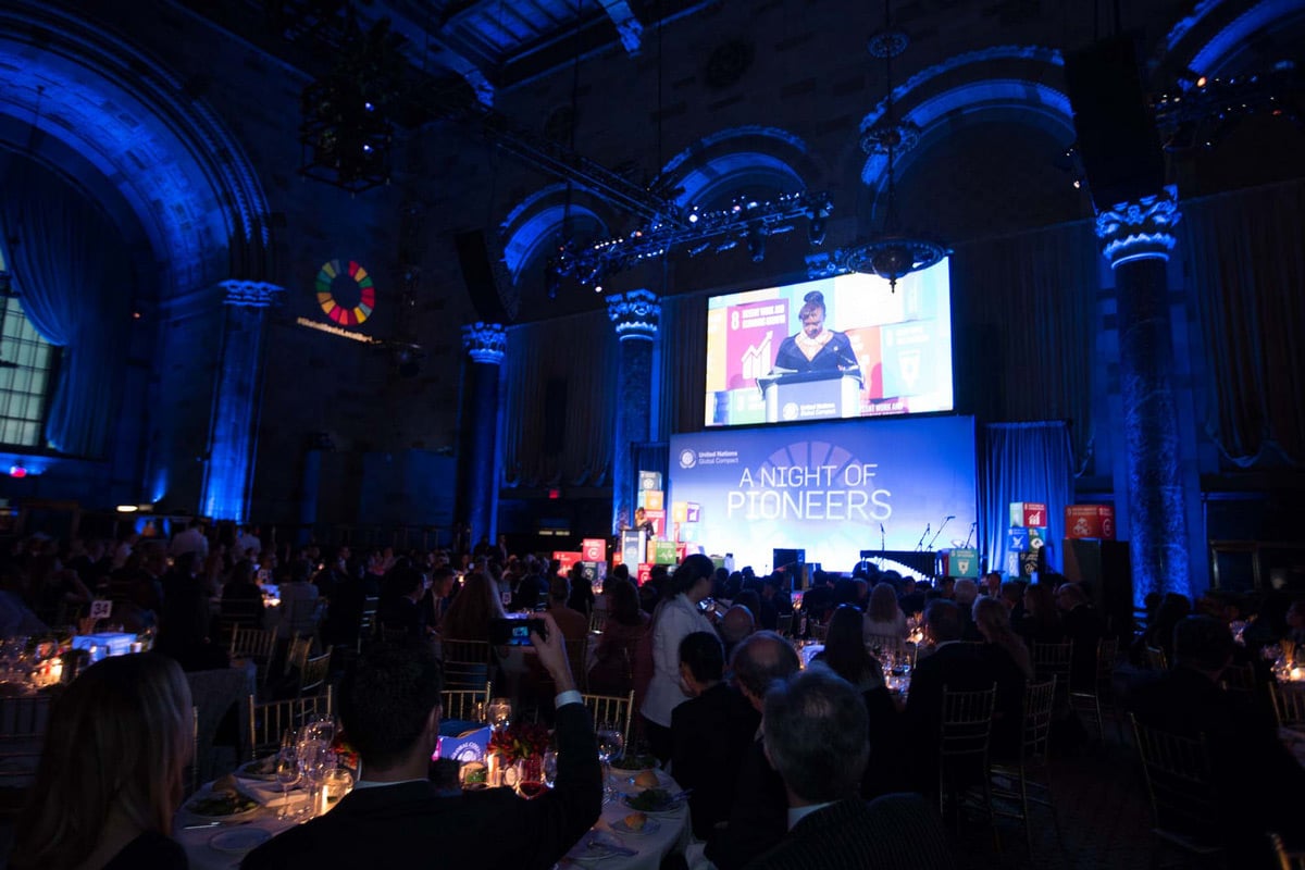 Evénement dans une grande salle de bal avec un éclairage bleu sur des colonnes ornées et une présentation scénique "Une nuit de pionniers".