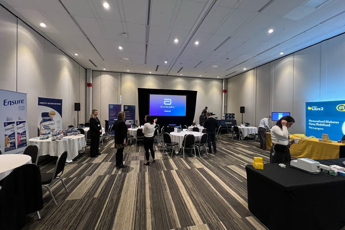 Salle d'exposition du salon avec le stand d'Abbott et les participants aux tables rondes
