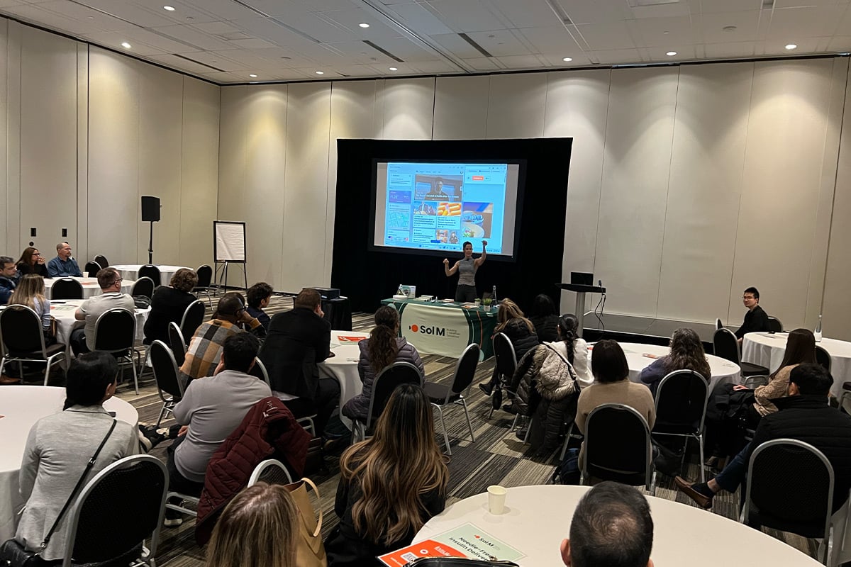 Présentateur s'adressant à un public assis dans une salle de conférence avec écran de projection